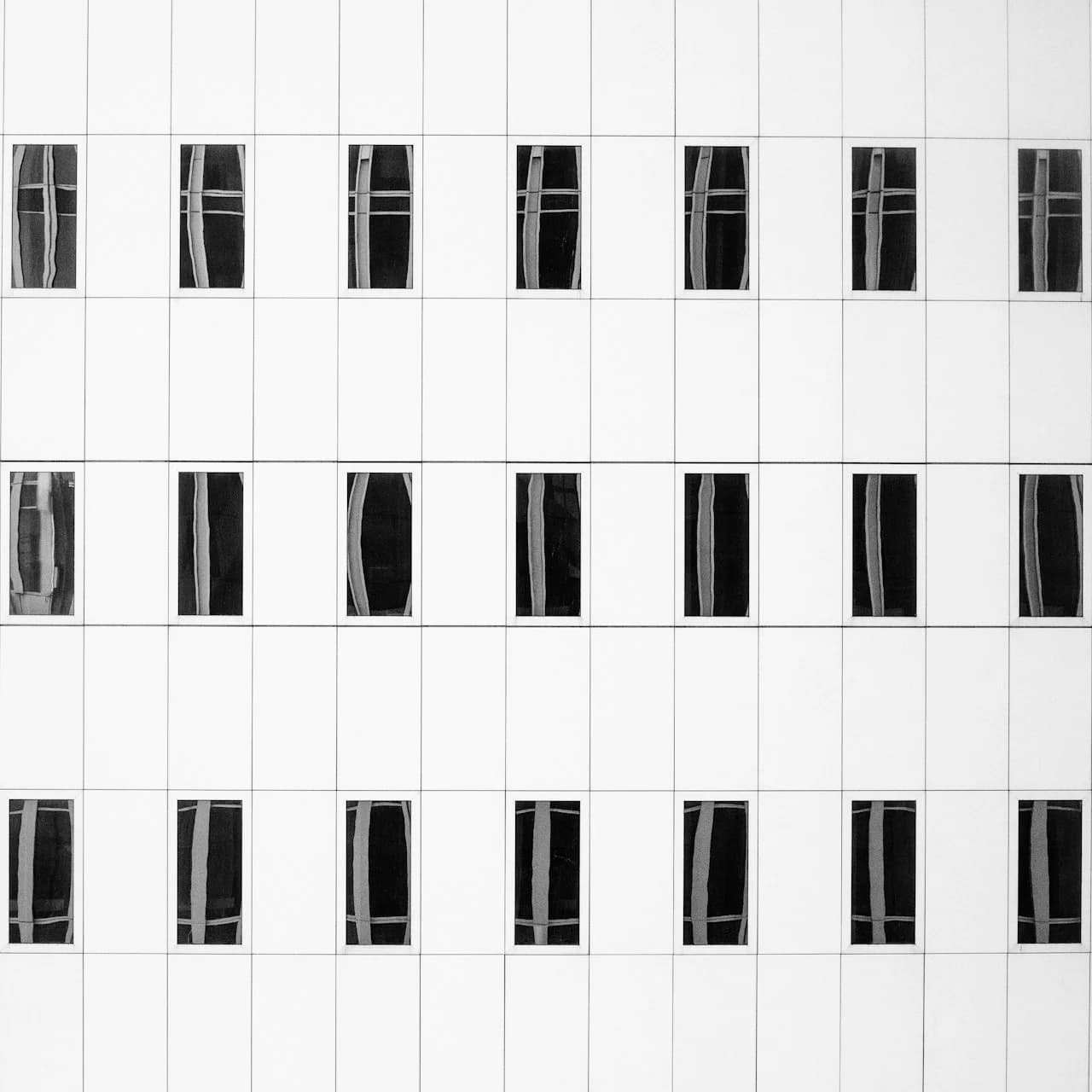 Štvorcové fotografie 15 × 15 cm v symetrickej mriežke na bielej stene