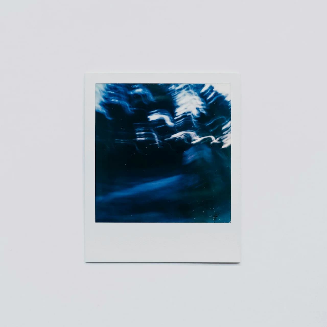 Kôpka štvorcových vytlačených fotografií podobných polaroidu na drevenom pozadí