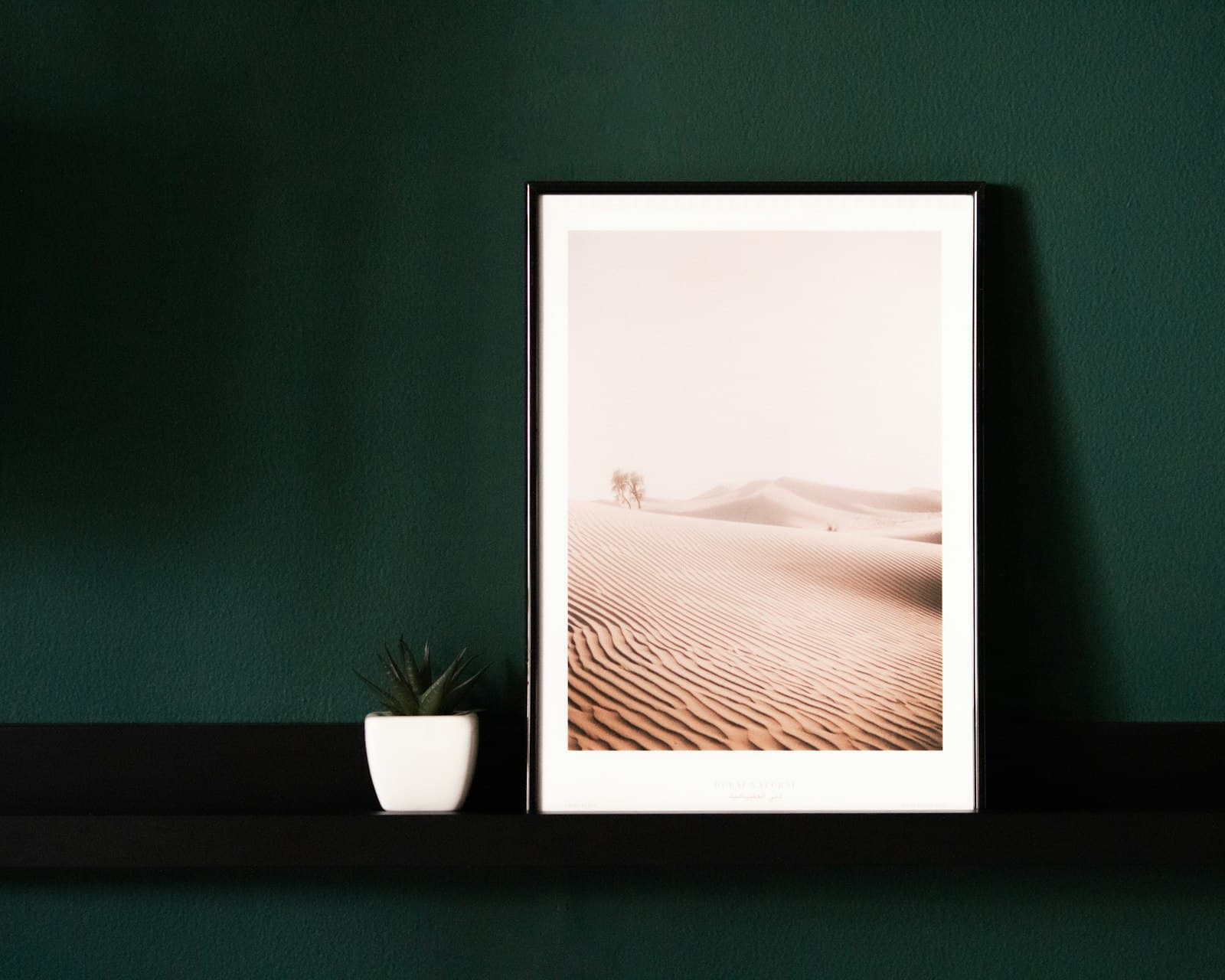 Veľká fotografia púšte v ráme na tmavozelenej stene