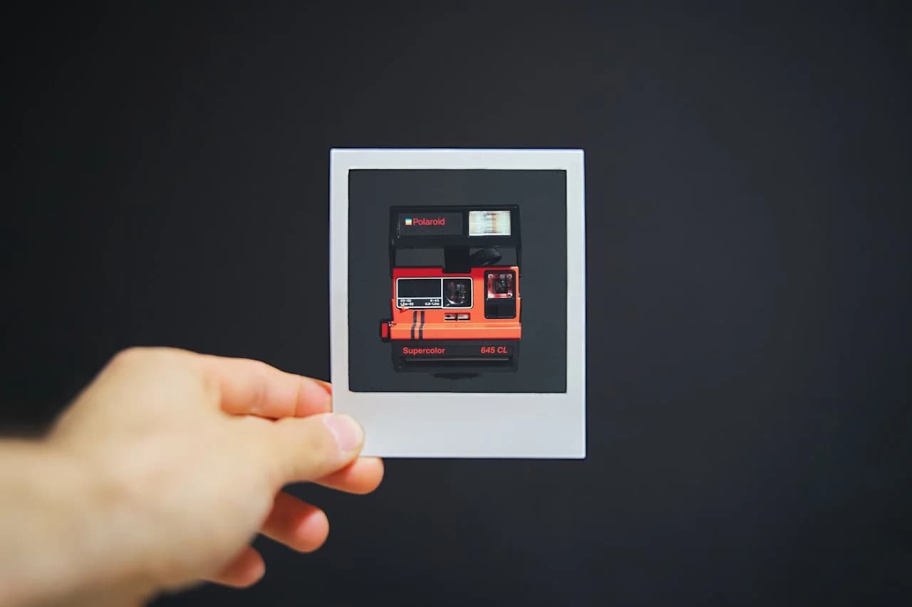 Ruka držiaca menšiu fotografiu polaroidového fotoaparátu