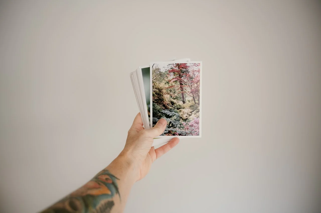 Ruky listujú fotoalbum plný vytlačených fotografií formátu 10 × 15 cm