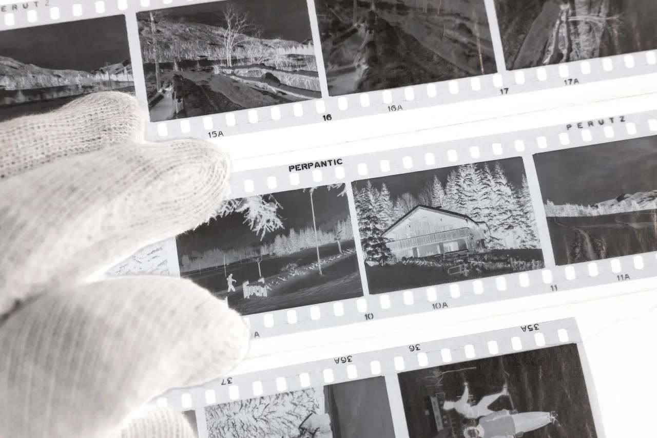 Ruka v rukaviciach, ktorá manipuluje so starými fotografiami