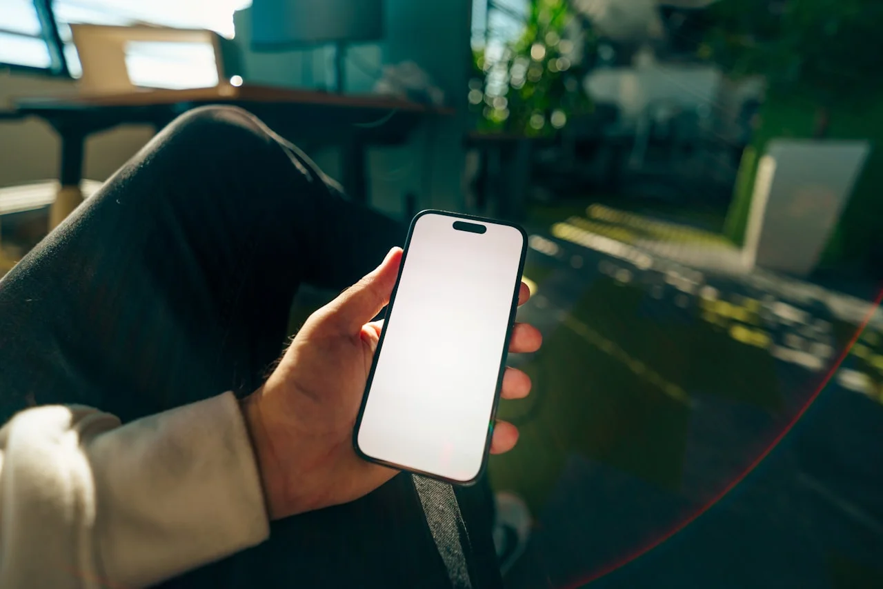 Ruka drží mobil s veľmi jasnou obrazovkou pri dennom svetle