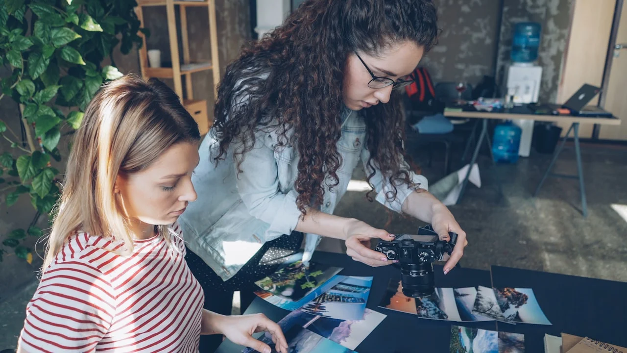 Dve ženy si vyberajú medzi vytlačenými fotografiami na pracovnom stole